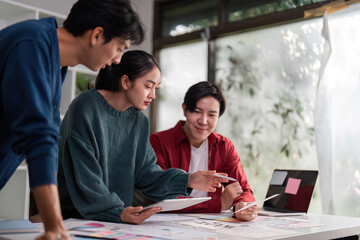 Collaborative Innovation in Design. A team brainstorming ideas around a table filled with design resources.