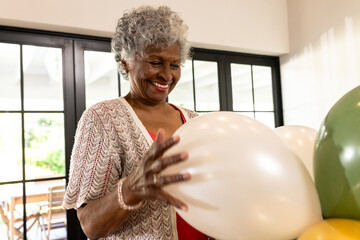 Arranging balloons for celebration, senior woman joyfully preparing at home