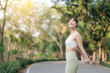 Asian woman stretching before workout outdoors in park, enjoying fresh air and sunlight surrounded by lush greenery. sport and healthy lifestyle concept