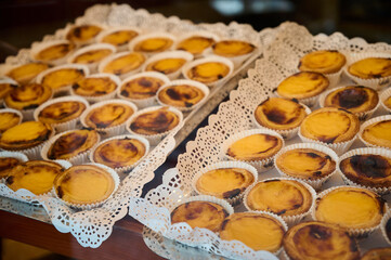 Freshly baked custard tarts displayed beautifully on lacy trays in a cozy bakery setting.