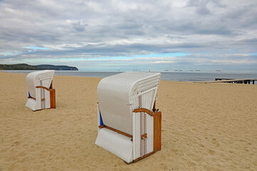 There are empty roofed wicker-style beach chairs, Baltic Sea beach, city of Sopot, Poland