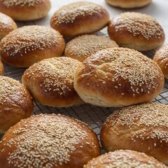 "A close-up of freshly baked buns sprinkled with sesame seeds, arranged neatly on a clean, white surface. The buns have a golden-brown crust with a soft, fluffy texture visible at the edges. The sesam