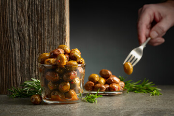 Spicy olives in a glass bowl on a stone table.