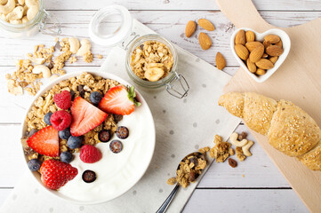 Muesli with organic berries and nuts, croissant. Oat muesli with raspberry, blueberry, strawberries, almond, cashew, banana. Healthy food, top view