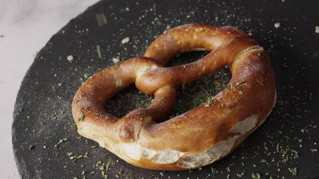 Footage of a Bavarian pretzel from the top. Dried herbs being sprinkled on the pretzel. Typical or traditional German, Bavarian food. Food footage.