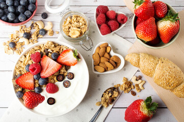 Muesli with organic berries and nuts, croissant. Oat muesli with raspberry, blueberry, strawberries, almond, cashew, banana. Healthy food, top view