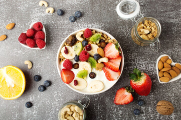 Muesli with organic berries and nuts. Oat muesli with raspberry, blueberry, strawberries, kiwi, almond, cashew, banana. Healthy food, top view