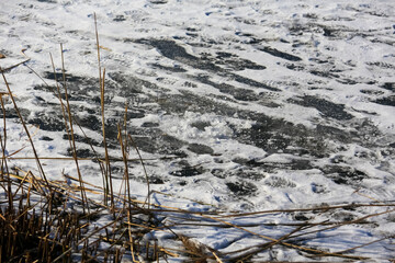 On the snow that covers the surface of the frozen lake, there are traces of people walking on the ice