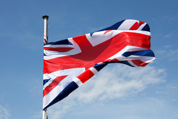 The flag of the United Kingdom flying against a blue sky
