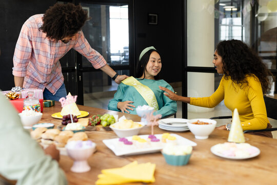 Celebrating baby shower, diverse friends sharing food and talking at office party