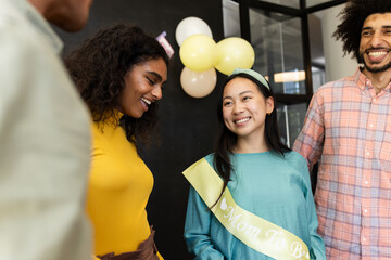 Celebrating at office, diverse colleagues smiling and chatting during baby shower