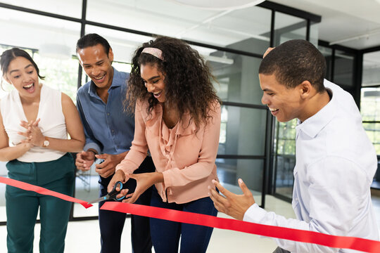 Diverse business team celebrating office opening with ribbon cutting ceremony
