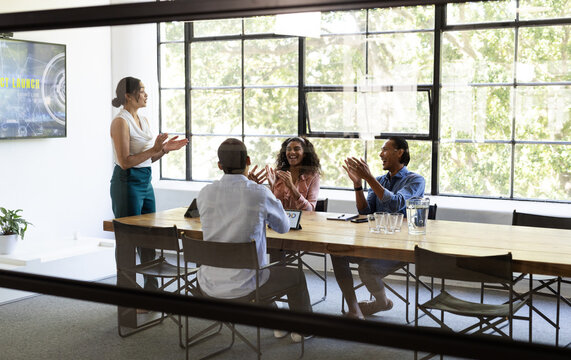 Business diverse team applauding colleague during presentation in modern conference room, at office