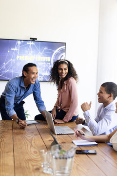 Diverse team discussing project launch in modern office, smiling and collaborating