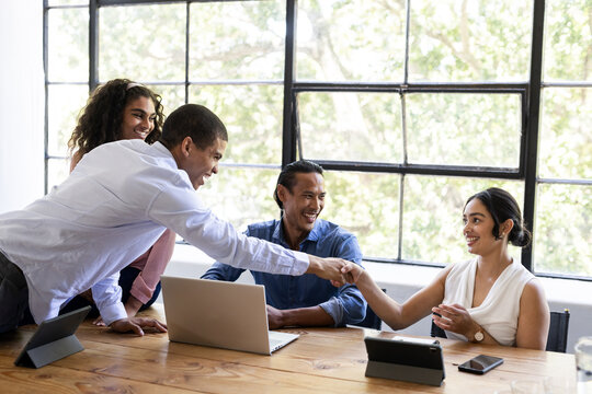 Diverse business team collaborating at office, shaking hands and smiling - Powered by Adobe