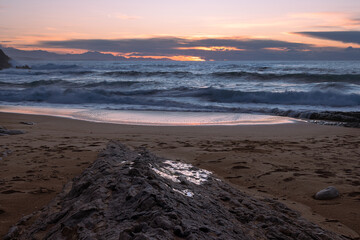 sunset on the beach with rock formation on the foreground