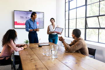 Discussing presentation, diverse business team in modern conference room setting, at office