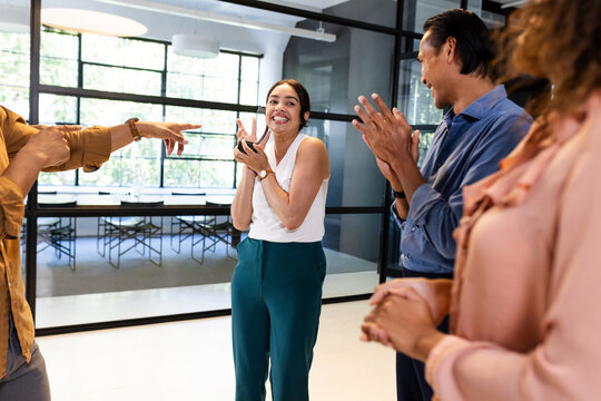 Diverse business team celebrating success, clapping and smiling in modern office