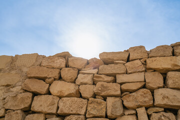 Ancient stone wall of the Step Pyramid of Zoser in Saqqara, Egypt, glows under the sun with a clear blue sky, whispering tales of history.