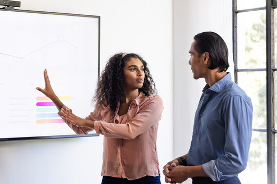woman presenting data on screen to colleague in office meeting