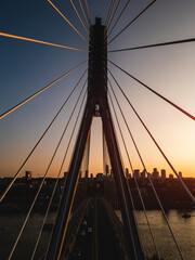 modern metal cable bridge over Vistula river at sunset, contemporary geometric architecture, cable-stayed bridge at city skyline, symmetry and architectural urban contrast, Warsaw