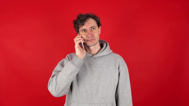 man answers phone, outraged annoying advertisements, refuses services offered, says no, becomes angry, aggressive, turns off call. Isolated red background, studio shot. concept - spam, phone surveys.