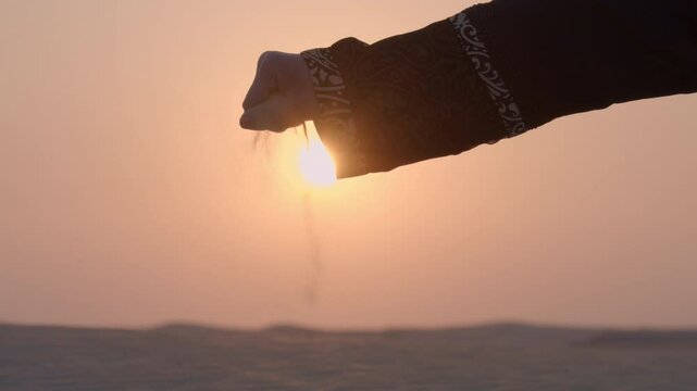 Arabic woman lady with Abaya cloth slow motion playing with sand during sunset in the desert sand dune