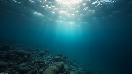 Fototapeta premium Underwater Sunbeams penetrate the blue water, rocks lie below surface