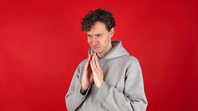 Mysterious sly curly man steeple fingers and schemes something tries to made up mind makes devious tricky plan isolated red background, studio shot. Evil genius action. Guy have idea. Planning evil.