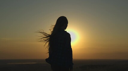 Woman is standing in the sun with her arms outstretched. Concept of freedom and joy, as the woman is embracing the warmth and light of the sun. The bright colors of the sky