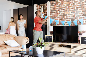 Baby shower, Man decorating living room with blue bunting for gender reveal party, at home