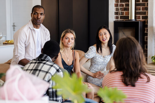 Diverse group of diverse friends enjoying conversation at home, smiling and relaxed
