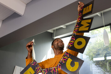 Man hanging welcome banner indoors, smiling and preparing for celebration