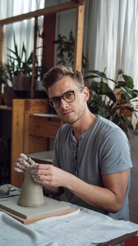 Attractive man in glasses is working on his own clay project.