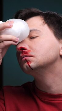 vertical video Man using ice pack on nose to stop bleeding after injury