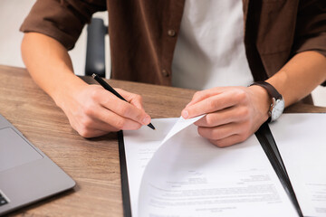 Client signing notarial document at wooden table in office, closeup