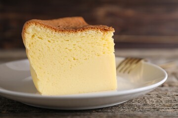 Piece of tasty Japanese Castella sponge cake and fork on wooden table, closeup