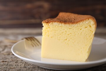 Piece of tasty Japanese Castella sponge cake and fork on wooden table, closeup