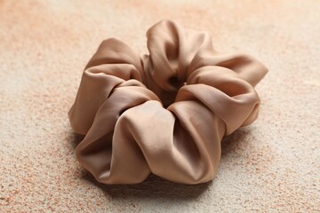 Beautiful hair scrunchie on color textured table, closeup