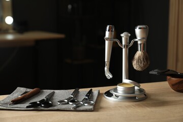 Many different barber's tools on light wooden table in barbershop