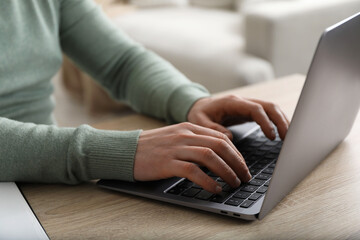 Man using laptop at desk indoors, closeup