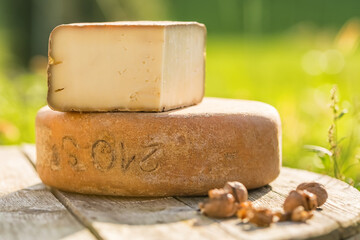 Traditional Ossau-Iraty cheese on a wooden table in the rural setting in France.