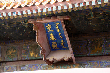 A close-up of a golden lettered sign under the ornate eaves in the Forbidden City, Beijing.