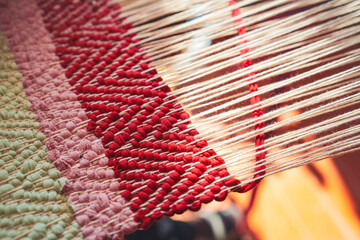 Traditional crafts: Close-up of a loom weaving, with woven silk using cotton and silk strings. The...