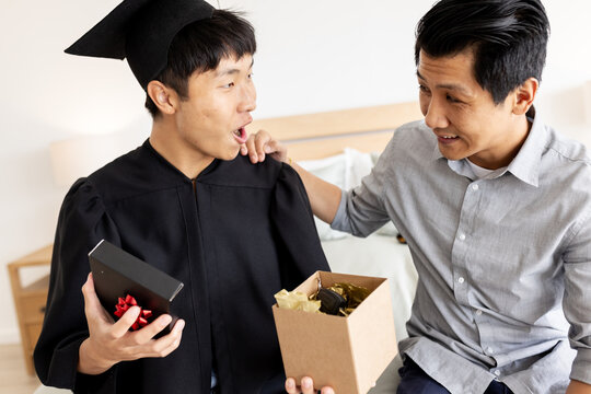 Celebrating graduation, Asian father and child with gifts and joy at home