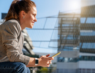 Side angle view of urban woman holding smartphone while sitting on street bench