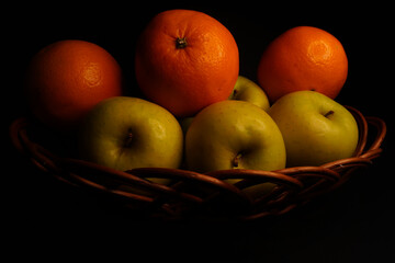 Basket of fruit (apples and oranges), taken with a predominance of lateral light that accentuates the shadows in an effect similar to chiaroscuro