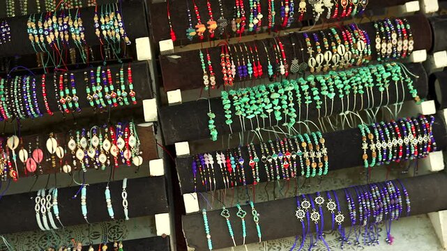 A vibrant collection of handmade beaded bracelets featuring colorful gemstones, shells, and charms displayed on a market stand, highlighting artisanal craftsmanship and cultural design.