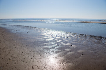 Sunlight reflecting on wet sand at beach on sunny day