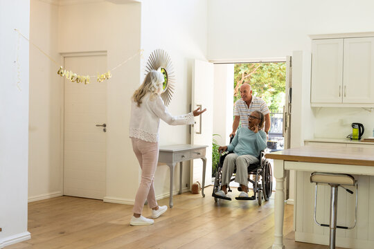 Arriving at home, senior diverse friends in wheelchair sharing joyful moments together, copy space